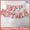 A string of 13 foil letter birthday balloons spelling out HAPPY BIRTHDAY, pink and gold, displayed against a white door.
