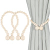 A set of two light wood magnetic bead curtain tiebacks against a gray fabric backdrop.