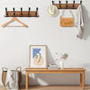 A wooden wall-mounted coat rack with five triple hooks is displayed above a wooden bench.