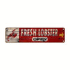 A weathered red metal sign for a fresh lobster business with an arrow pointing right.