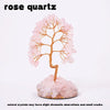 A pink rose quartz crystal tree stands on a base, showcasing natural crystals with slight chromatic aberrations and small cra
