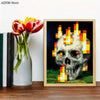 An unframed art print featuring a pixelated skull with flames on a dark background, displayed next to a vase of red tulips.