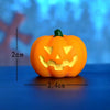 An orange Halloween resin craft miniature pumpkin with a carved face and green stem.