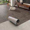 Roll of 3D textured wood grain self-adhesive flooring film laid on a light floor.