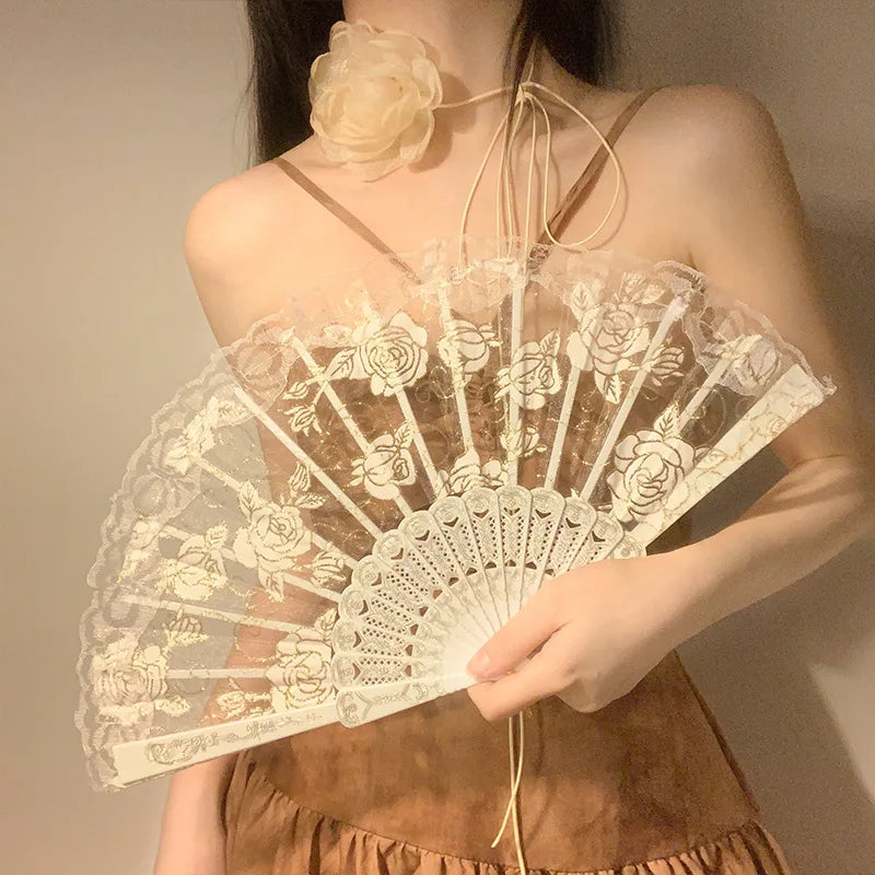 A woman holds an elegant white lace rose folding fan against a neutral background.