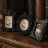 Three vintage resin mini picture frames displayed on a wooden surface next to old books.