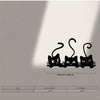 Black metal wall decor featuring three stylized cats with curled tails.