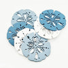 A set of twelve wooden ocean ornaments featuring various sea shapes like shells, scallops, and starfish in shades of blue and