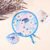 A round, light blue fabric fan with pink and white floral and geometric patterns is shown next to a dried flower branch.