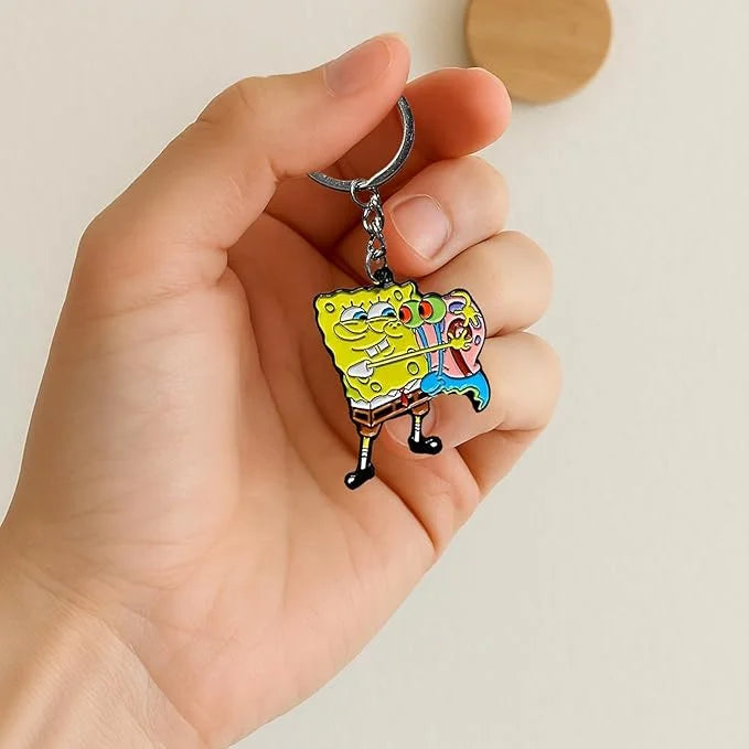 A hand holds a cartoon keychain featuring SpongeBob SquarePants in yellow and pink colors.