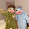 Two people in fuzzy monster onesies pajamas, one green and one blue, posing together.