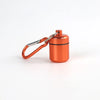 A small, round, copper-colored pill organizer is attached to a silver keychain ring.