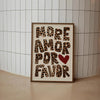 A framed canvas print featuring the text More Amor Por Favor in a leopard print font with a red heart symbol.