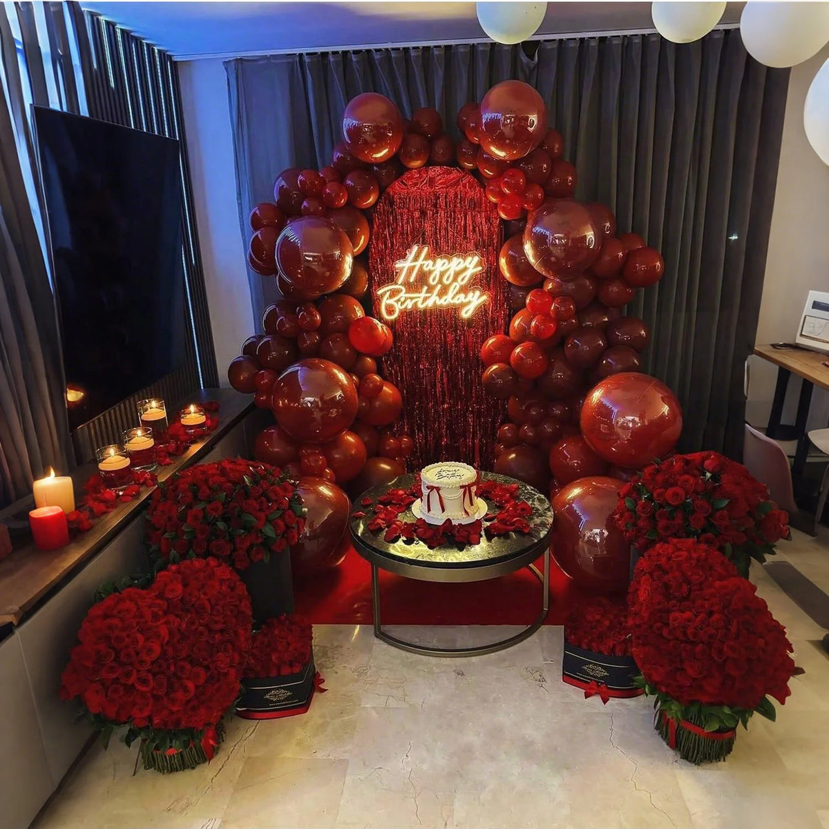 A large balloon arch decoration featuring ruby red balloons and a sign that reads Happy Birthday.