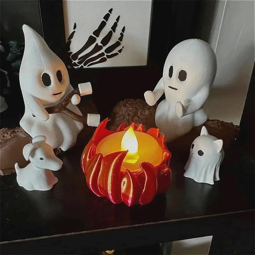 A set of white ghost figures and a red campfire decoration on a dark surface.