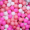 A pile of colorful, glossy plastic balls in pink, white, and magenta for play areas.