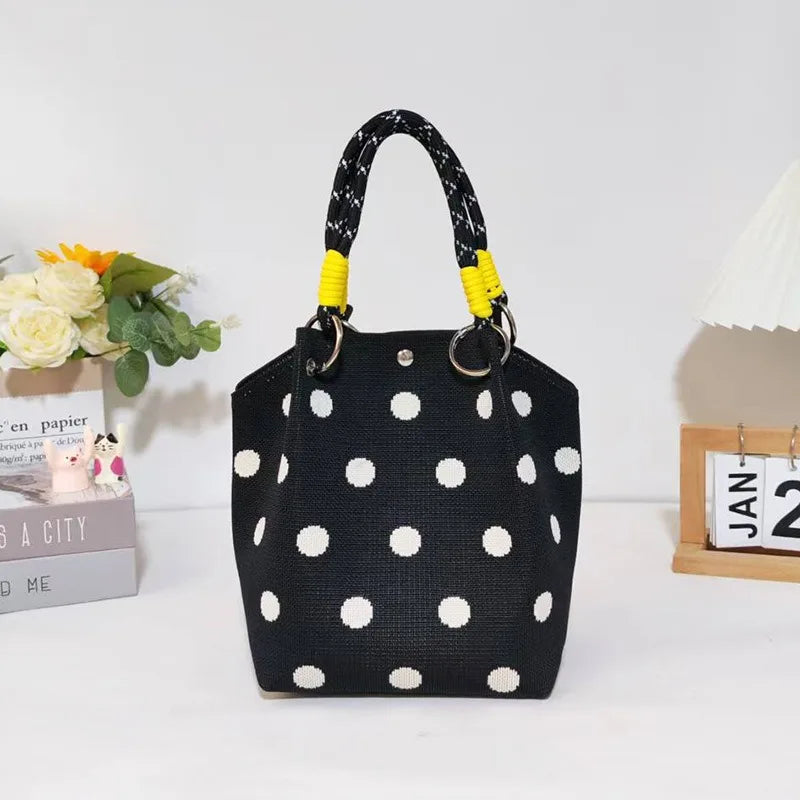 Black canvas shoulder bag with white polka dots and yellow braided handles