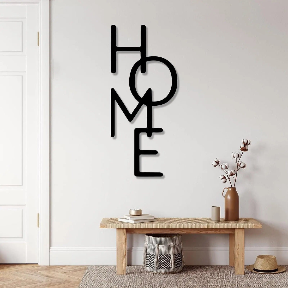 Black metal word art spelling out HOME mounted on a white wall above a wooden table.