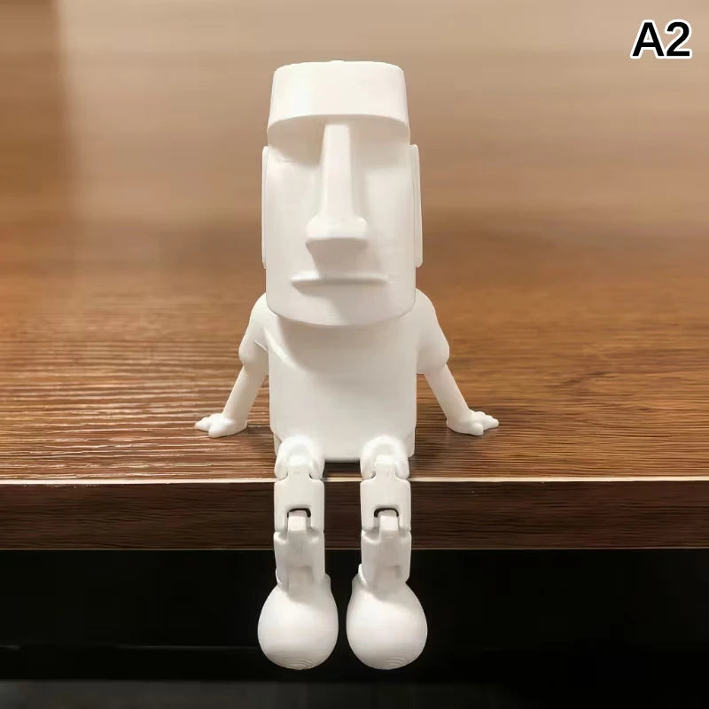 A white 3D printed Moai statue figurine with movable joints standing on a wooden surface.