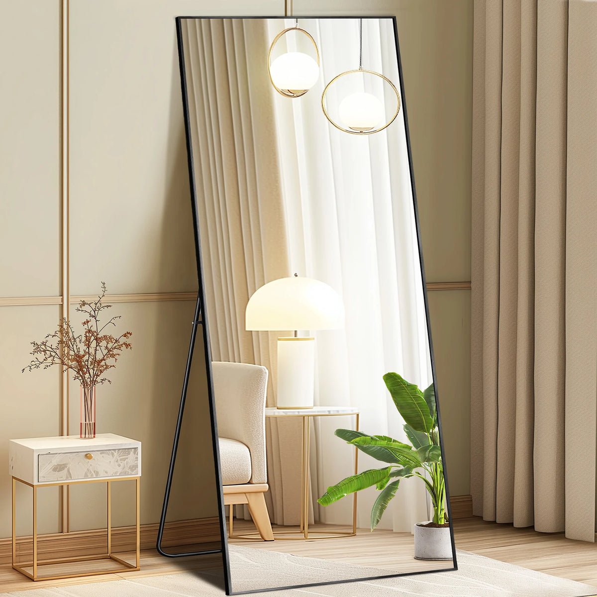 A full length arched wall mirror reflects a bright interior with hanging spherical lights and a potted plant.