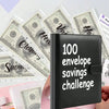 A black leather savings planner binder is shown next to stacks of US dollar bills.