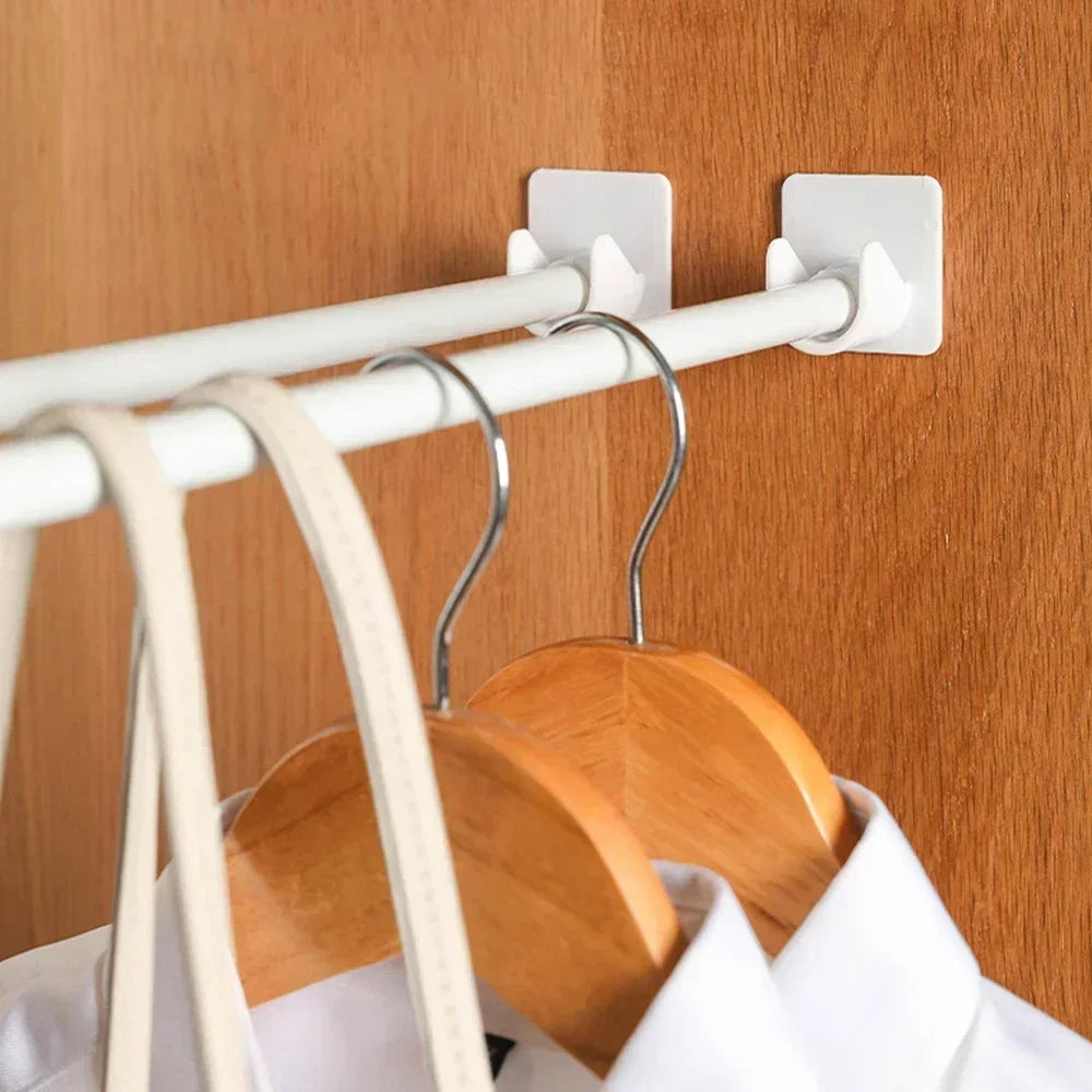 A wooden coat hanger is hanging from a white curtain rod mounted on a wall.