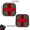 Two embroidered medical cross tactical morale patches, one olive green and red, shown with a hook and loop.