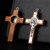 A wooden crucifix pendant with a detailed depiction of Christ on the cross, hanging from a silver loop.
