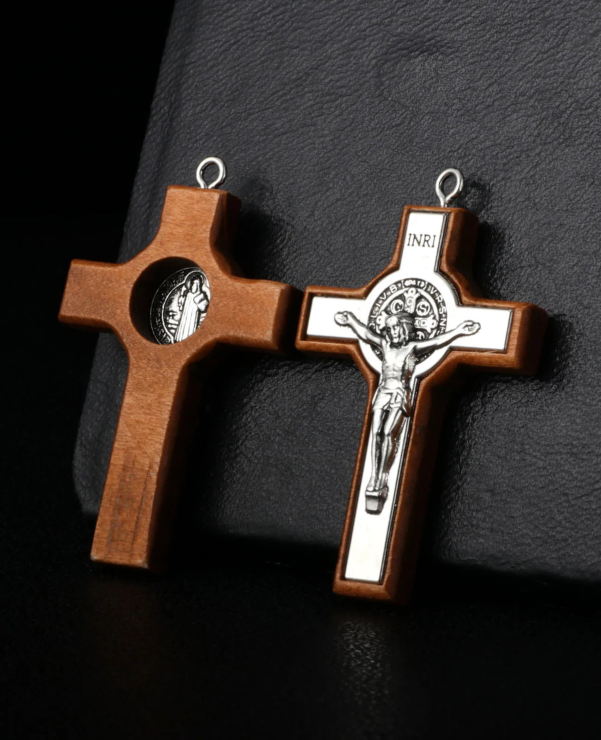 A wooden crucifix pendant with a detailed depiction of Christ on the cross, hanging from a silver loop.