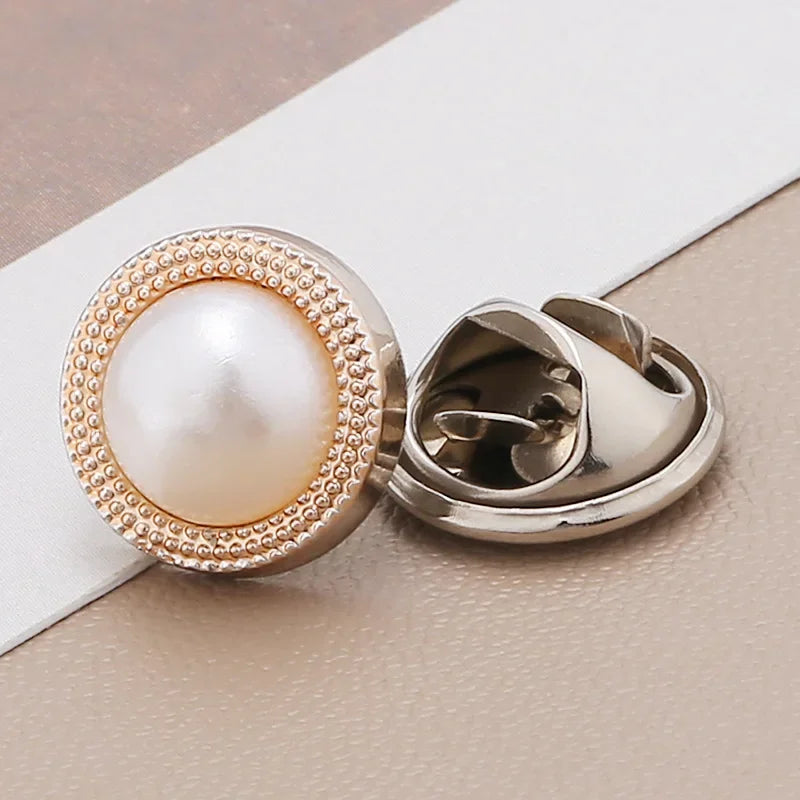 A close-up of a pearl and rhinestone no-sew brooch button with a gold-toned setting.
