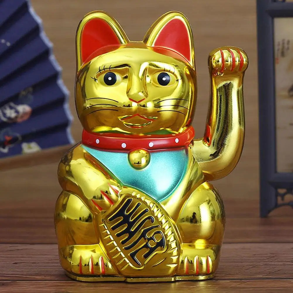 A golden animated electric fortune cat decor figurine sitting on a wooden surface.