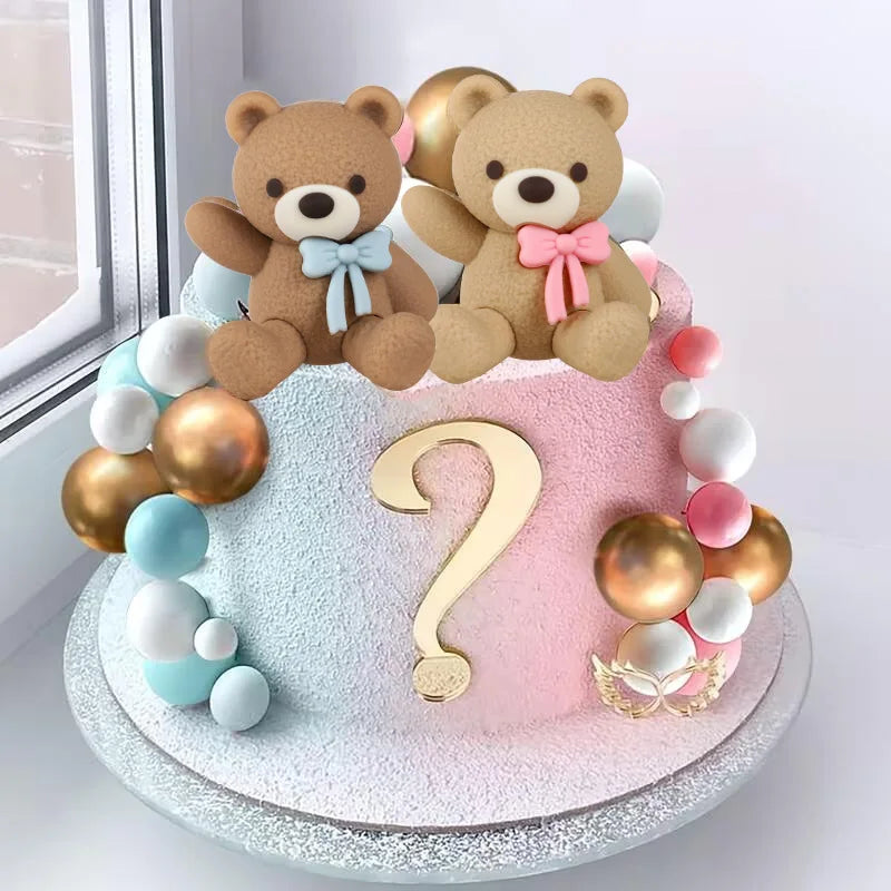 A tiered cake decorated with teddy bear toppers in brown and pink colors for a gender reveal party.