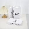 A set of three modern decorative fake books in white, featuring the text love where life begins and love family.