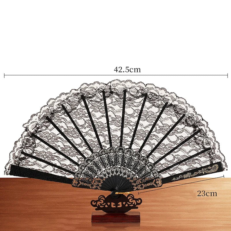 An elegant black and white lace folding hand fan displayed on a wooden surface.