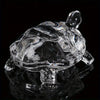 Clear crystal turtle desk ornament reflecting on a dark surface.