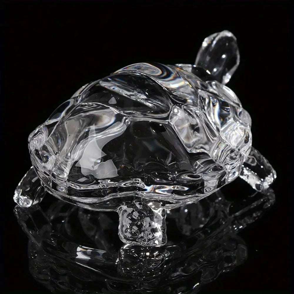 Clear crystal turtle desk ornament reflecting on a dark surface.