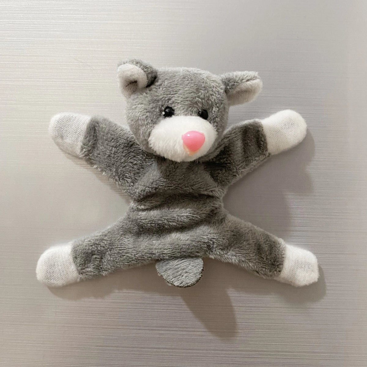 A gray plush toy resembling an elephant with a pink nose, used as a fridge magnet.