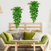 Artificial pothos hanging vines used as wall decor above a wooden bed frame with green and beige pillows