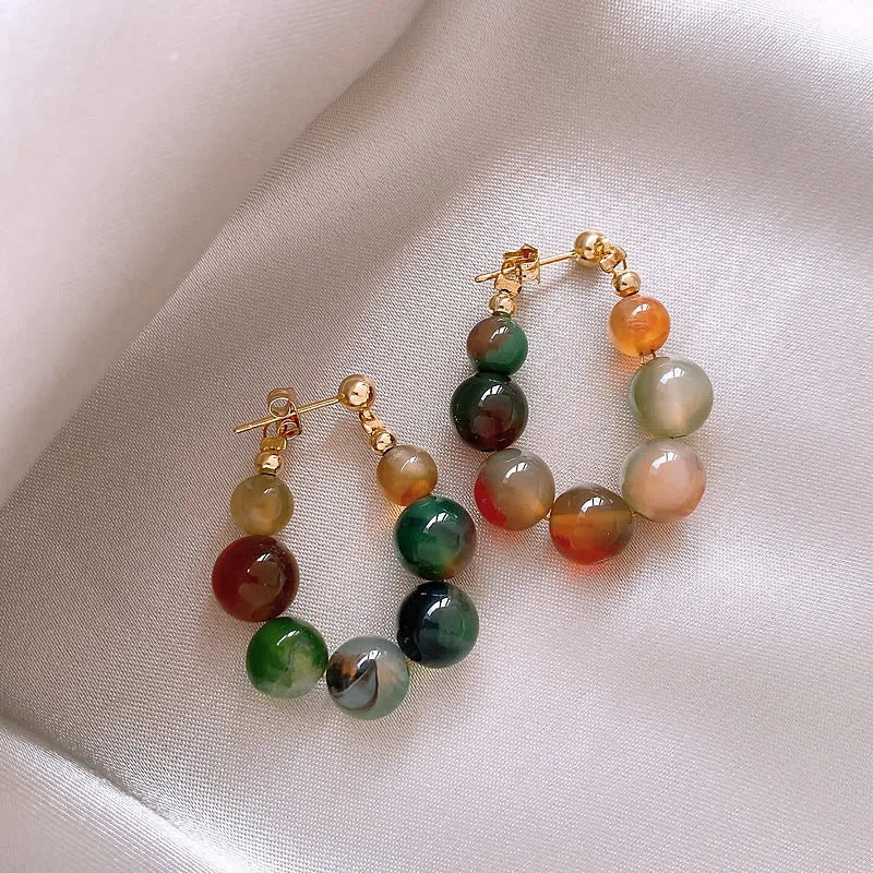 Gold-toned resin beaded drop earrings featuring various shades of green and amber stones.