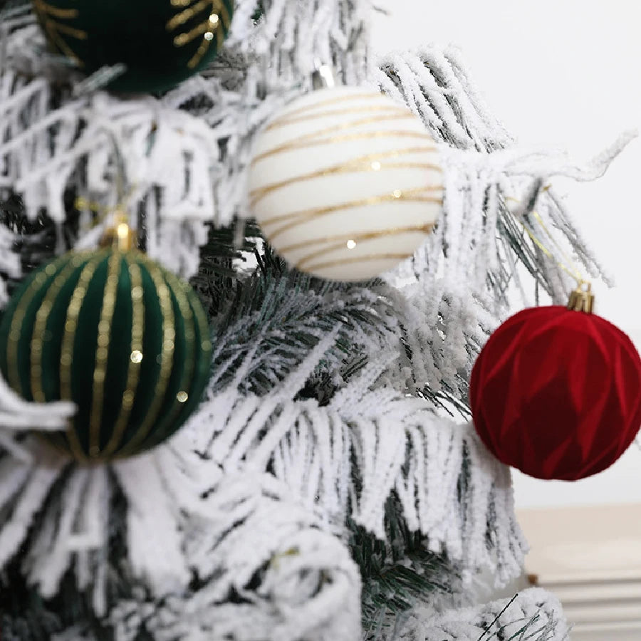 Close-up of a white flocked Christmas tree decorated with gold and red velvet ornaments.