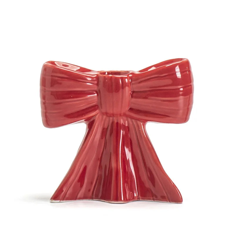 A glossy red ceramic bow candle holder with a flared base.