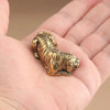 A vintage brass tiger figurine, a miniature animal statue, is held in a person's hand.