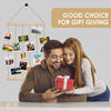 Un couple regarde une boîte cadeau rouge devant un collage de photos en bois rustique.