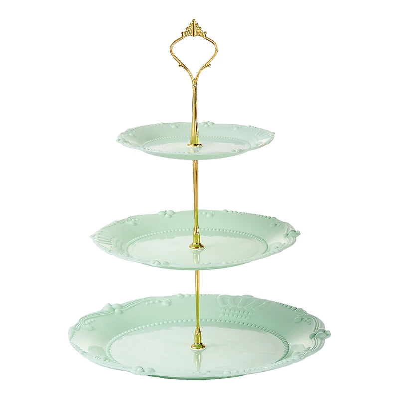 A three-tier plastic cupcake stand with a gold-toned metal topper and light mint green plates.