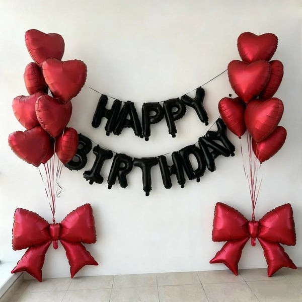 A decorative banner made of black heart balloons spelling out HAPPY BIRTHDAY with red balloons and bow accents.