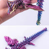 A hand holds a purple and pink 3D printed articulated dragon fidget figurine with spiky scales.