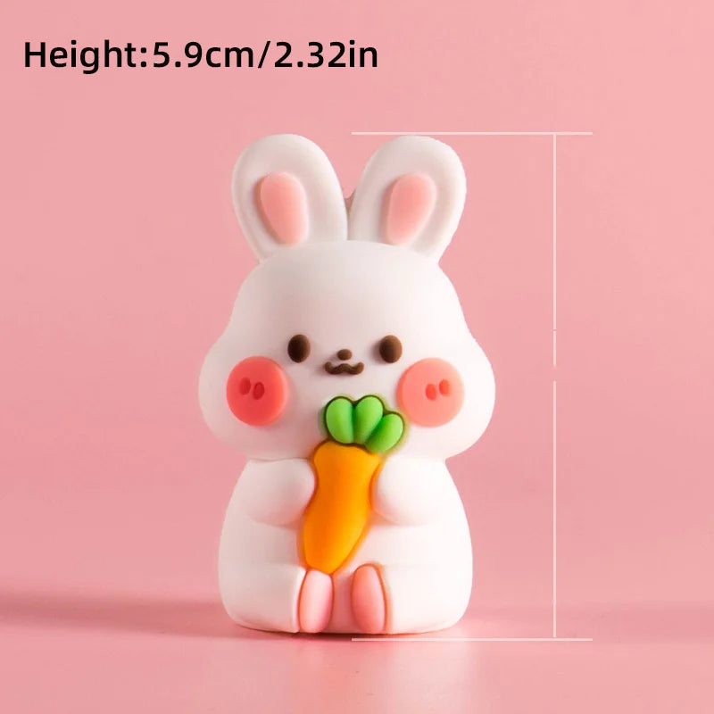 A white, cute rabbit-shaped cake topper with pink accents and an orange carrot decoration.