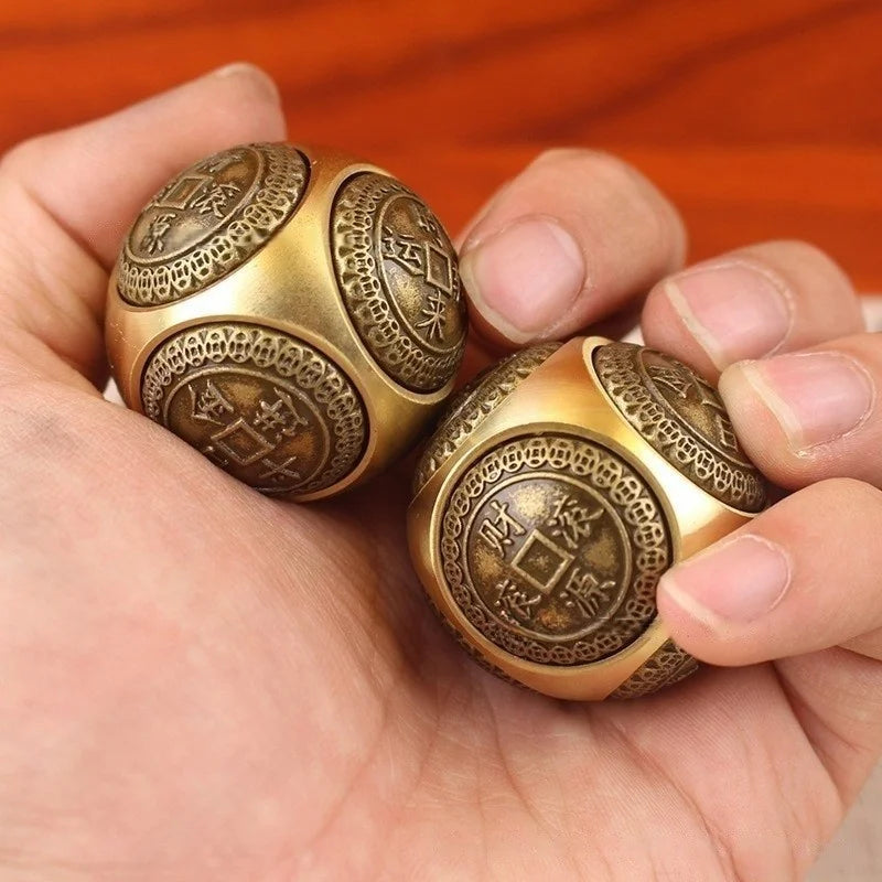 A hand holds two golden Chinese lucky coin spinners, featuring intricate patterns and Chinese characters.