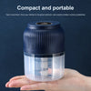 A clear plastic mini food chopper with a dark blue lid is held in a person's hand.