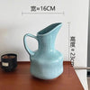 A light blue ceramic pitcher or vase with a handle, measuring about 16cm in diameter and 23cm in height.